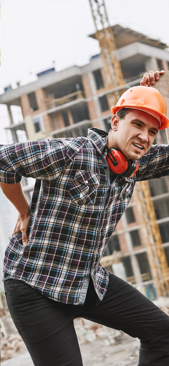 Construction worker in protective helmet feeling back pain while working at construction site